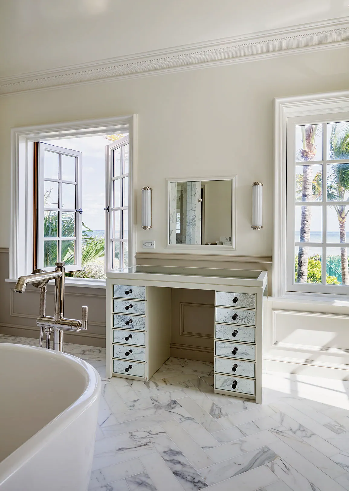 Freestanding tub and a mirrored vanity desk under casement windows