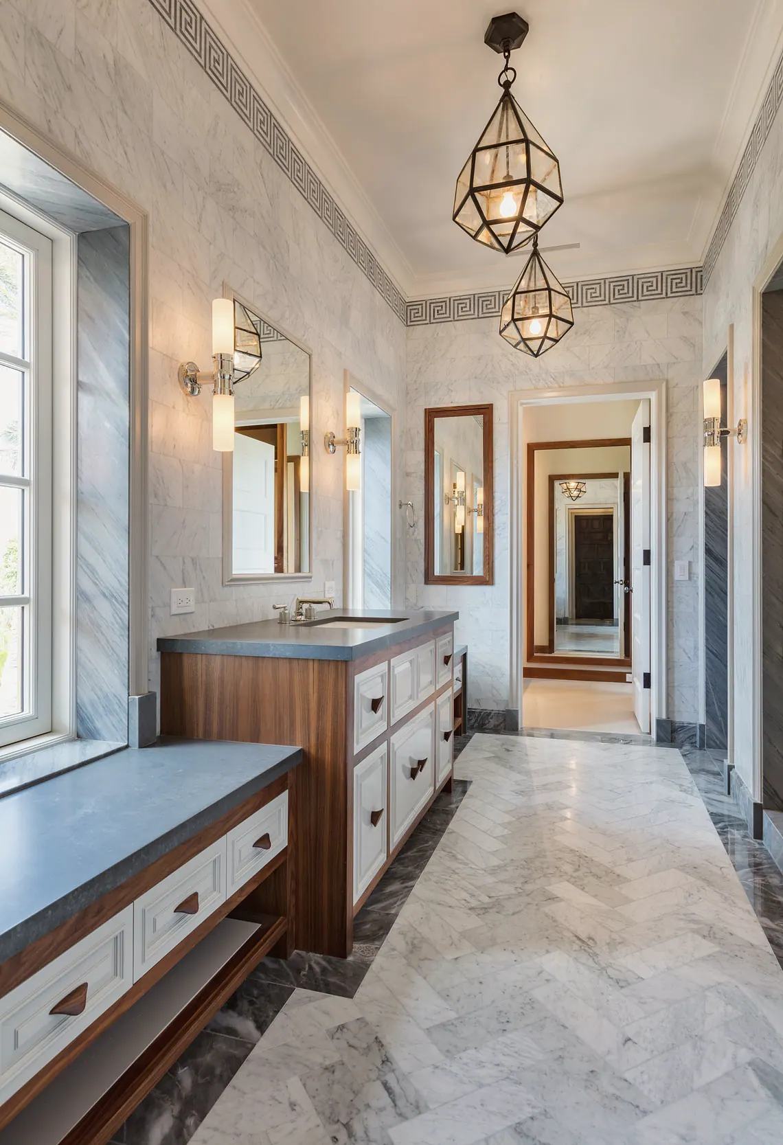 Long marble bath with a walnut vanity and lantern pendants