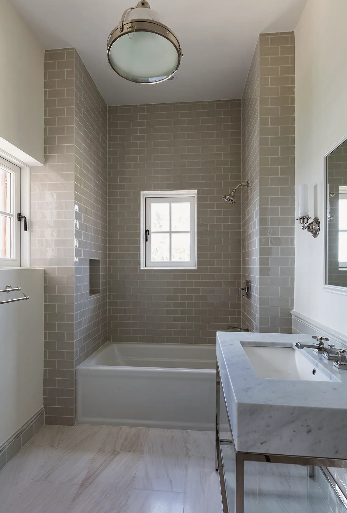 Gray subway tile bath with a tub and a console sink
