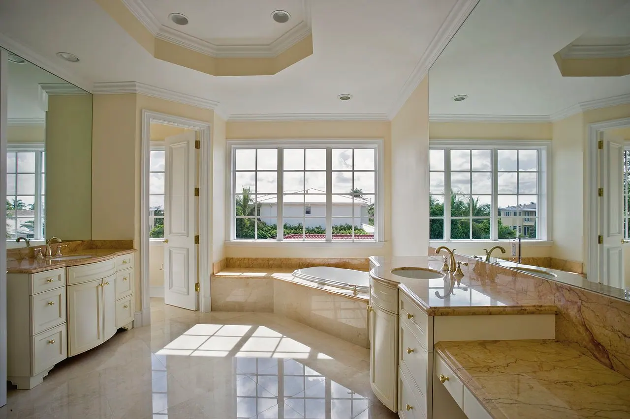 Primary bath with twin vanities and a corner tub under a wall of windows