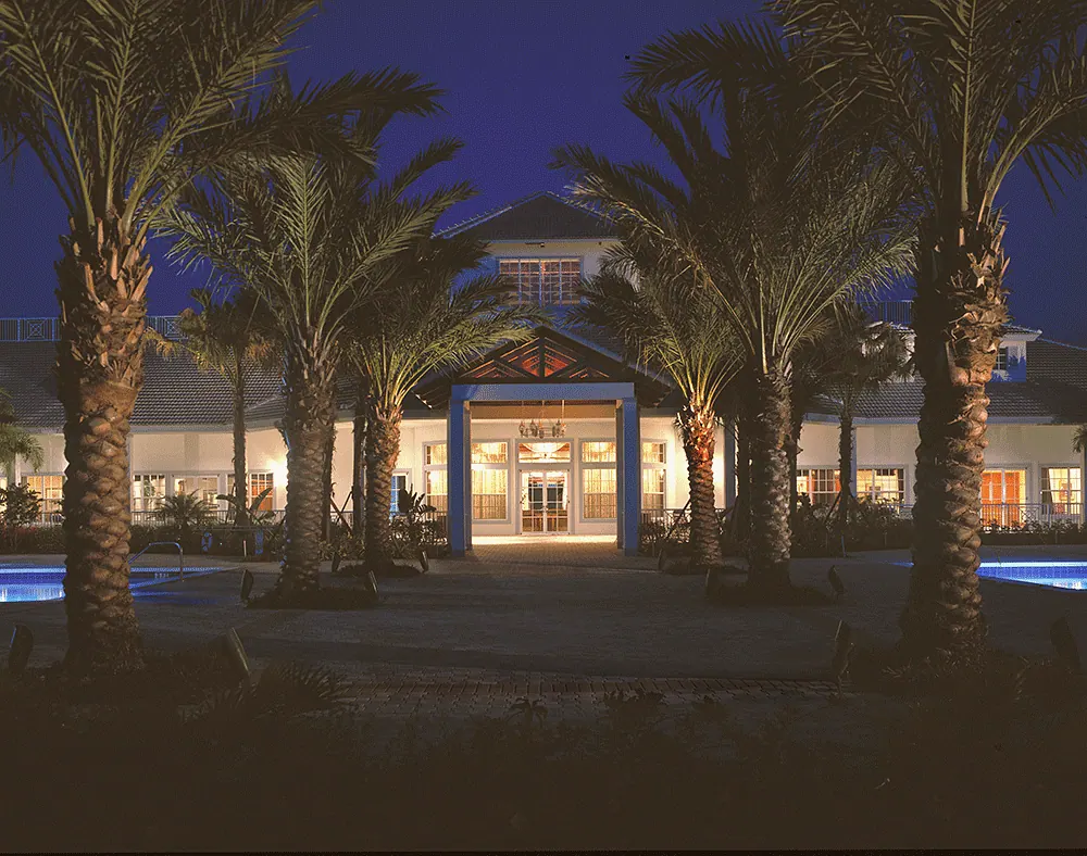 Clubhouse entry lit at night, framed by palms