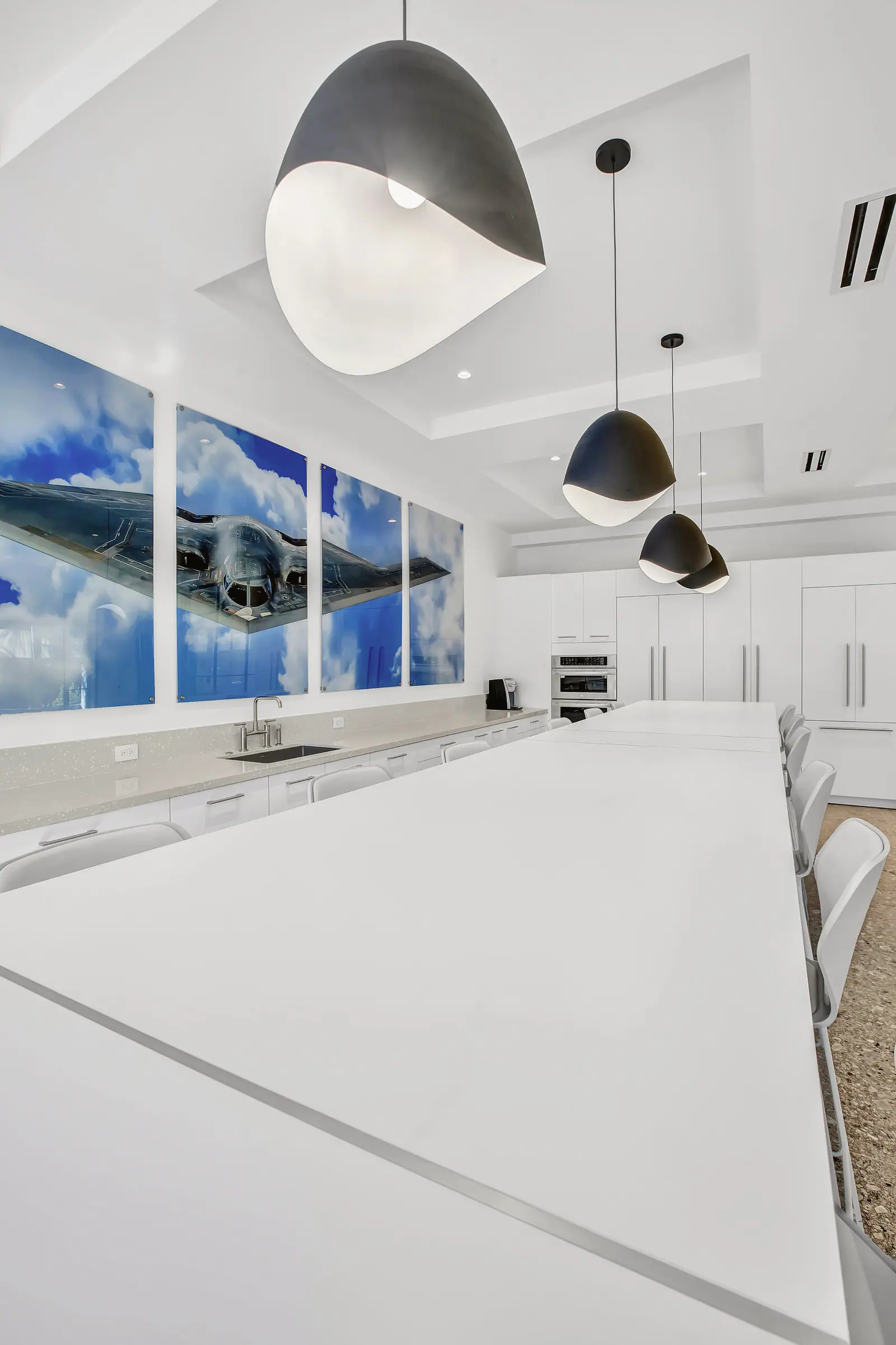 Long white conference table under sculptural pendant lights