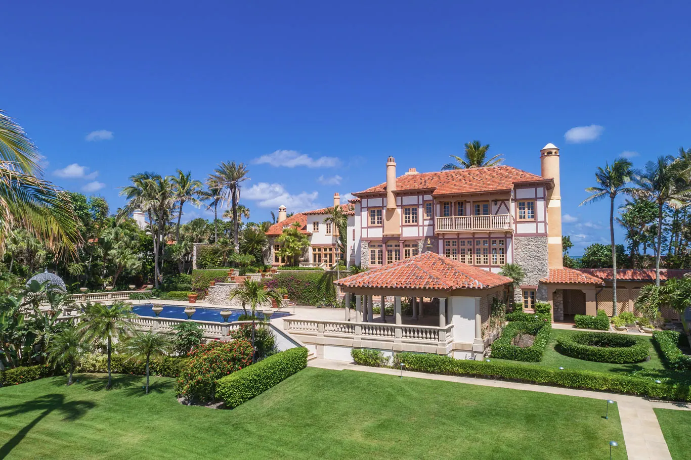Red tile roofed estate with a pool pavilion and a formal lawn