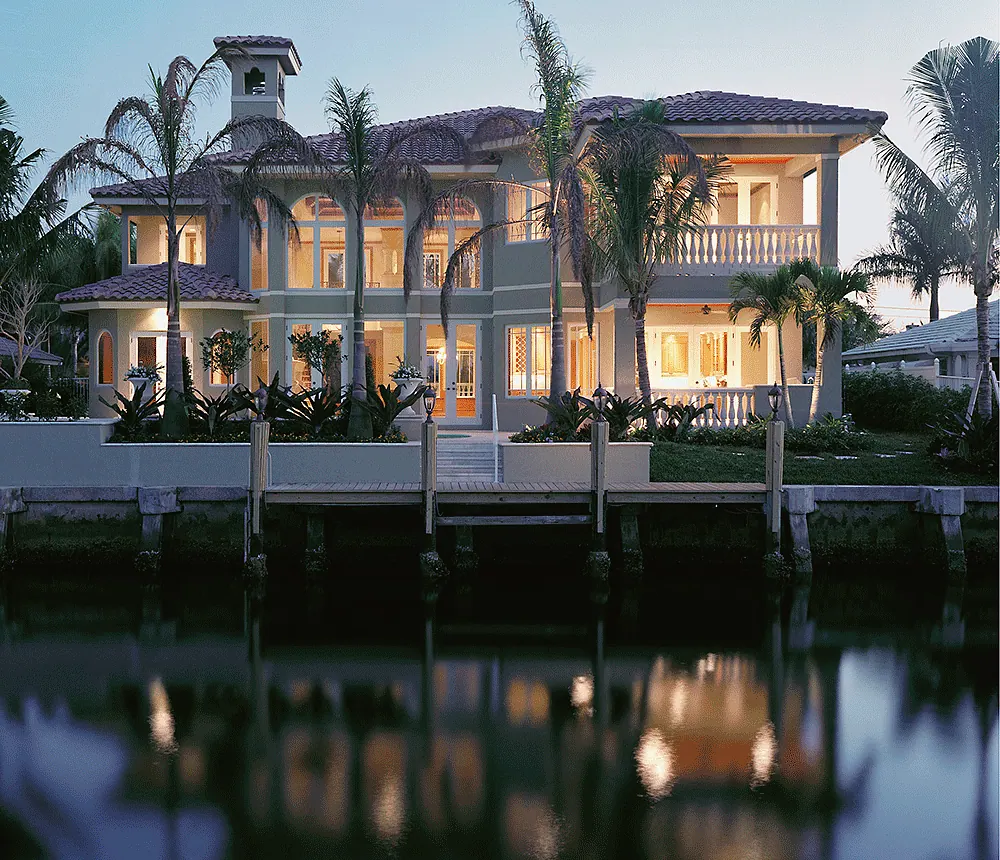 Waterfront house lit at dusk, reflected in the water