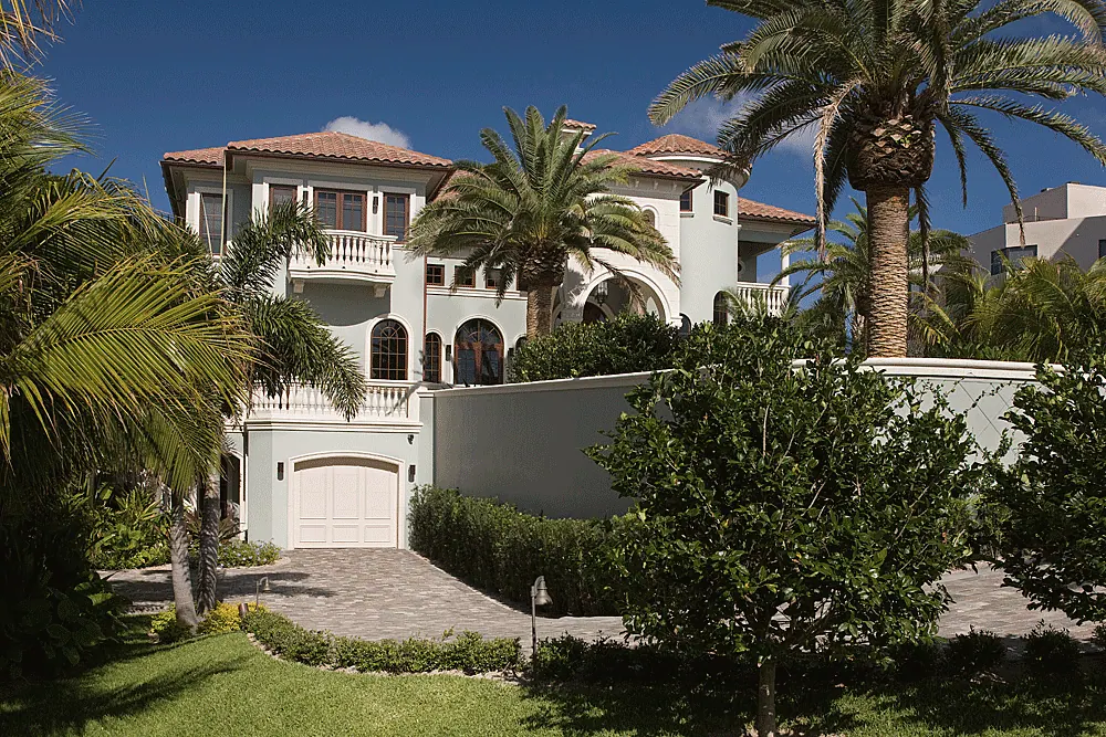 White stucco house with tile roofs set among palms