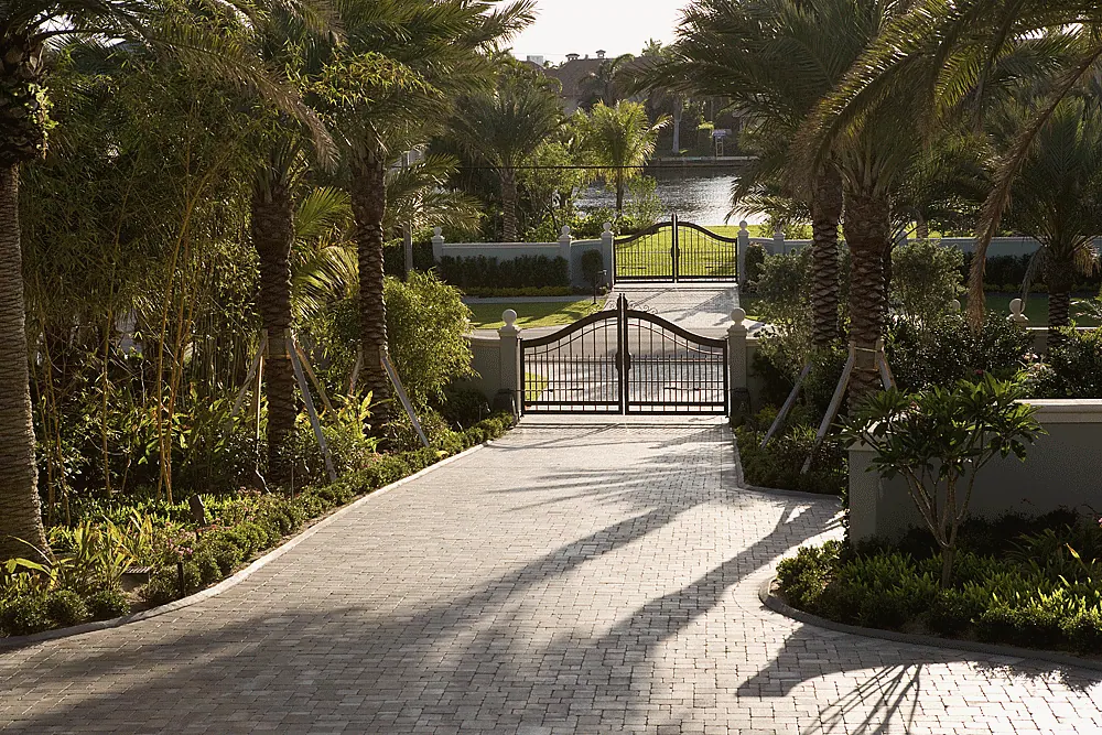 Paver drive through a garden to an iron gate