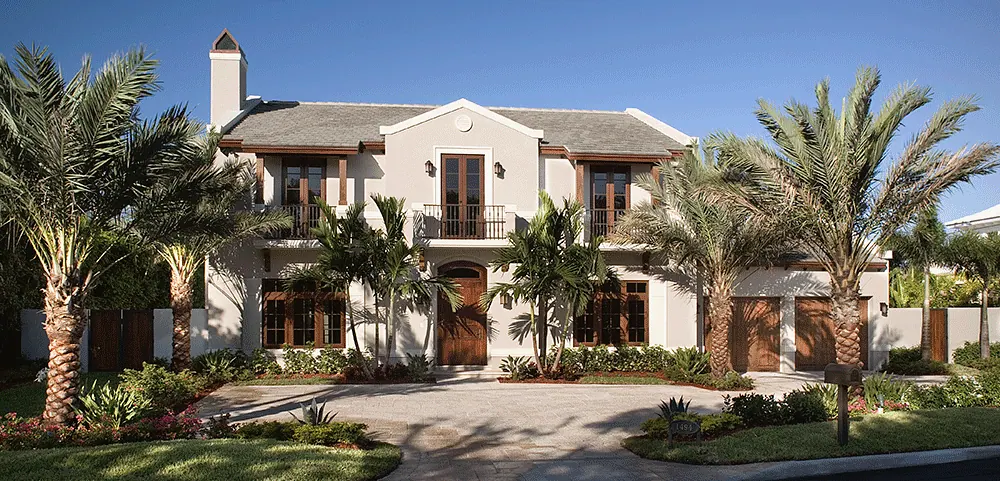 White house with dark shutters, palms and a circular drive