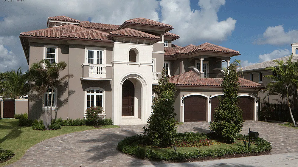Two-story Mediterranean house with a tile roof, an arched entry and a paver drive