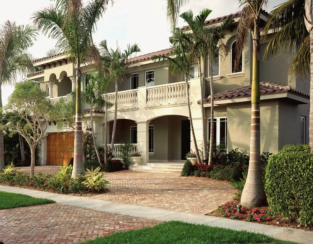 Two-story Mediterranean house with a balustraded balcony and a herringbone paver drive