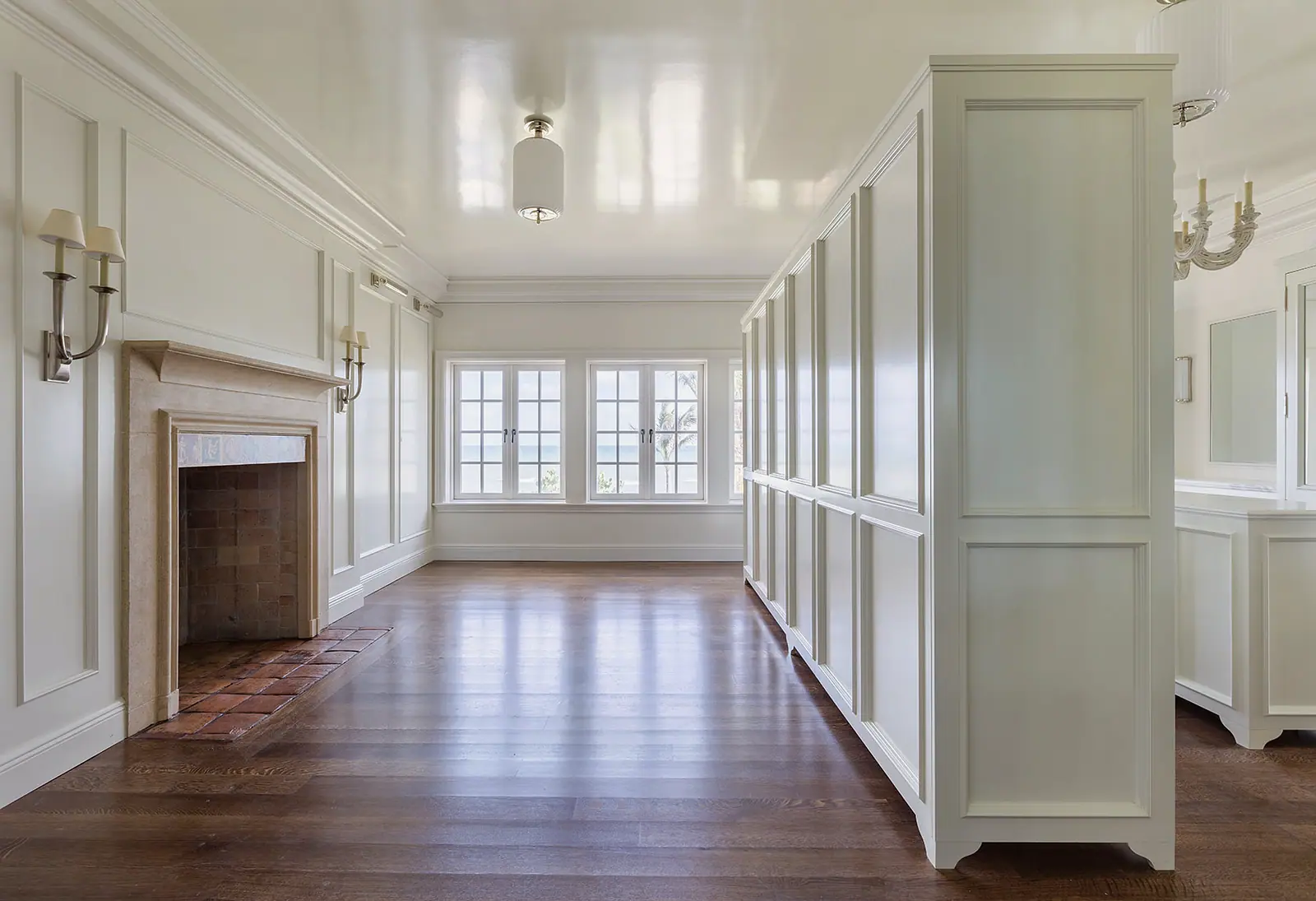 Paneled room with a fireplace, wide-plank floors and built-in cabinetry
