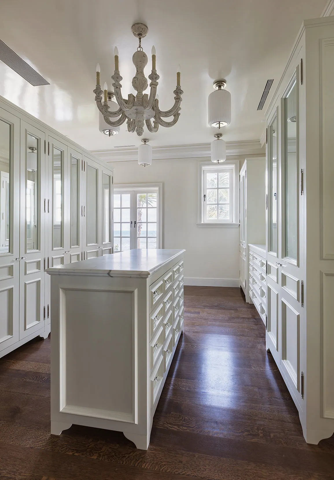 Long dressing room with paneled wardrobes on either side of an island