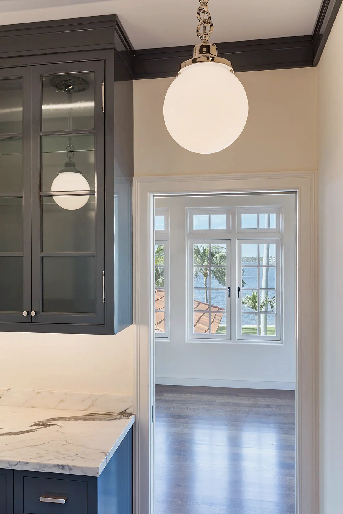 Pantry with dark glass-front cabinets and a globe pendant, a doorway to the water