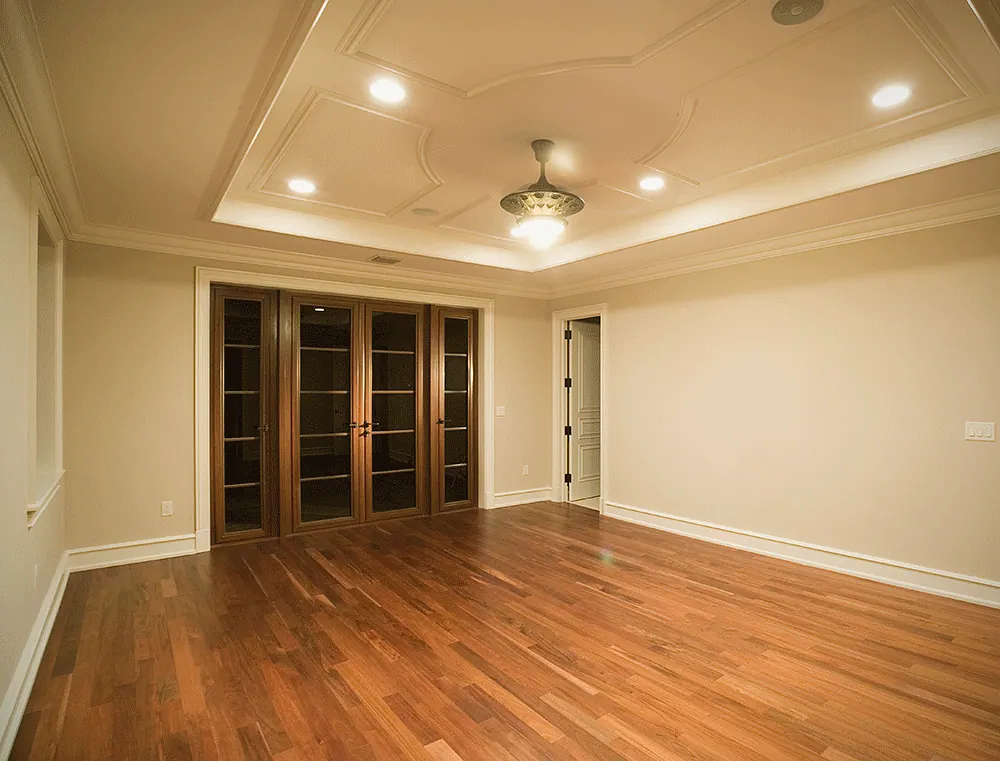 Finished room with a stepped tray ceiling, a plank floor and a row of French doors