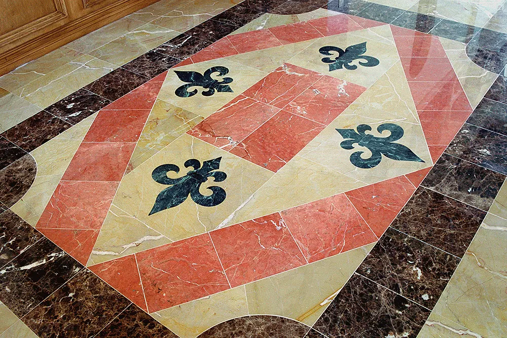 Marble floor inlay with fleur-de-lis in red, cream and dark stone