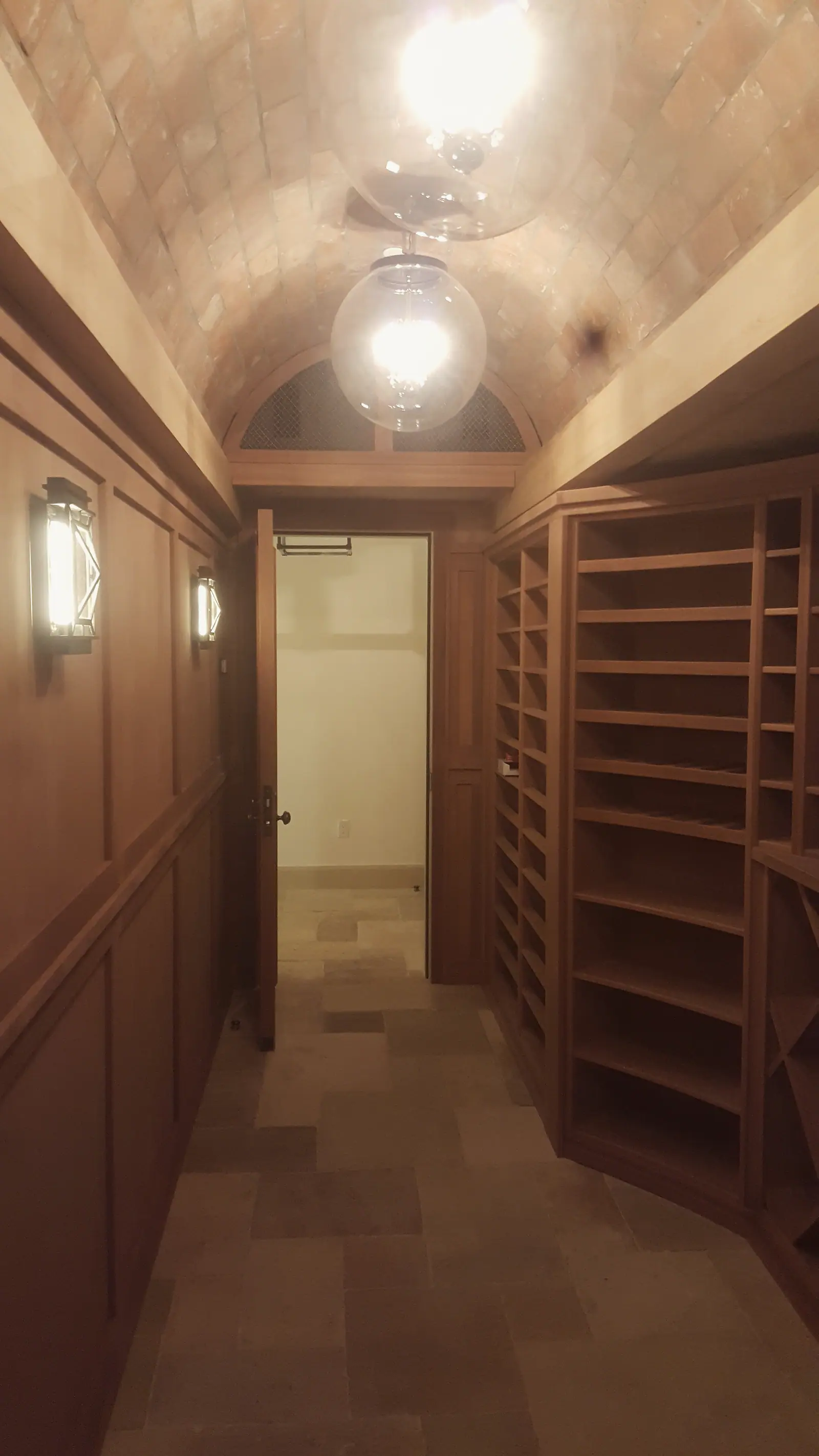 Wine cellar with a brick barrel vault, mahogany racks and paneling and a stone floor