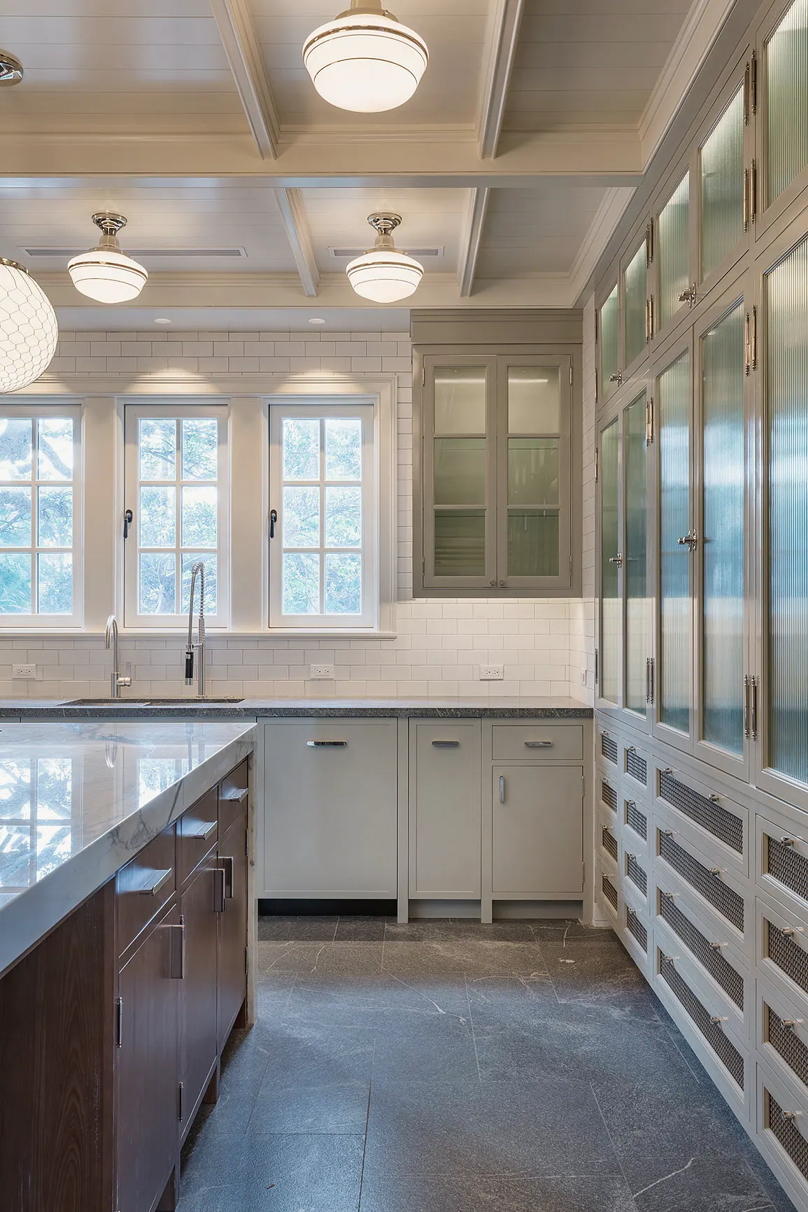 White kitchen under a coffered ceiling with pendant lights