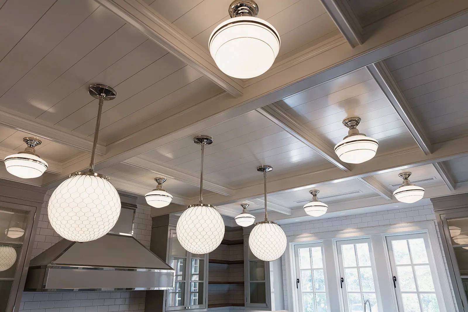 Coffered kitchen ceiling with globe pendants over a steel hood