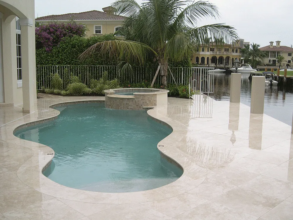 Freeform pool on a marble deck by the water