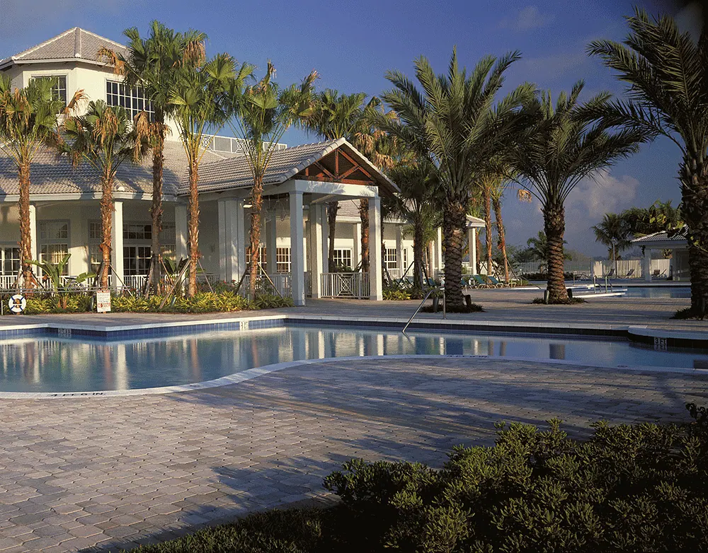 Pool and pavers in front of a clubhouse lined with palms