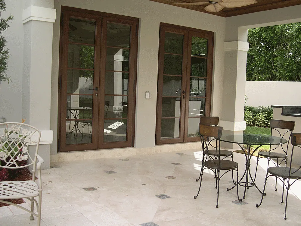 Covered loggia with French doors, a travertine floor and a bistro table
