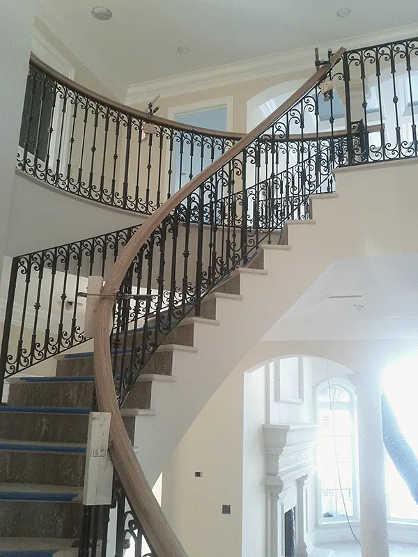 Curved stair with a wrought iron railing, before finishes