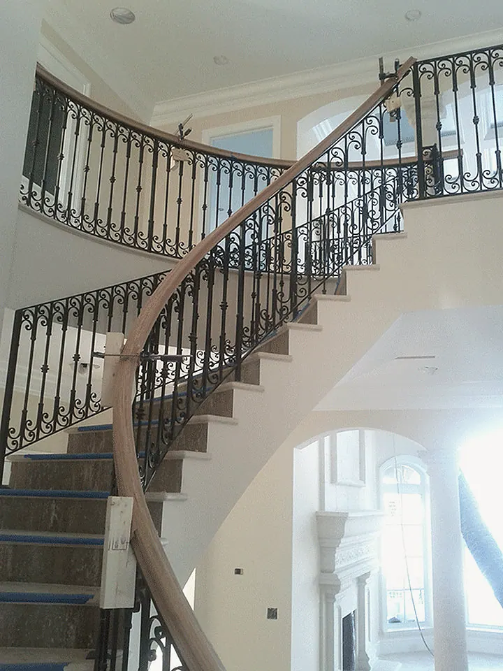 Curved stair with a wrought iron railing, the treads still protected