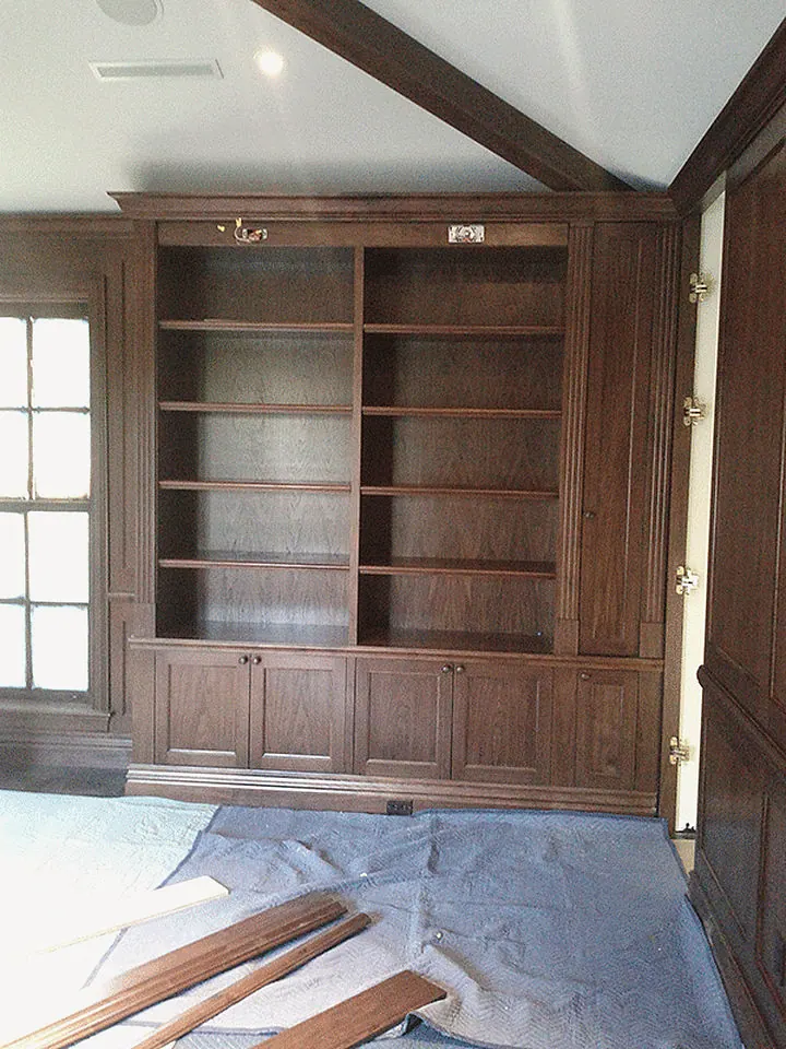 Dark wood library built-ins just installed, the floor under protection paper