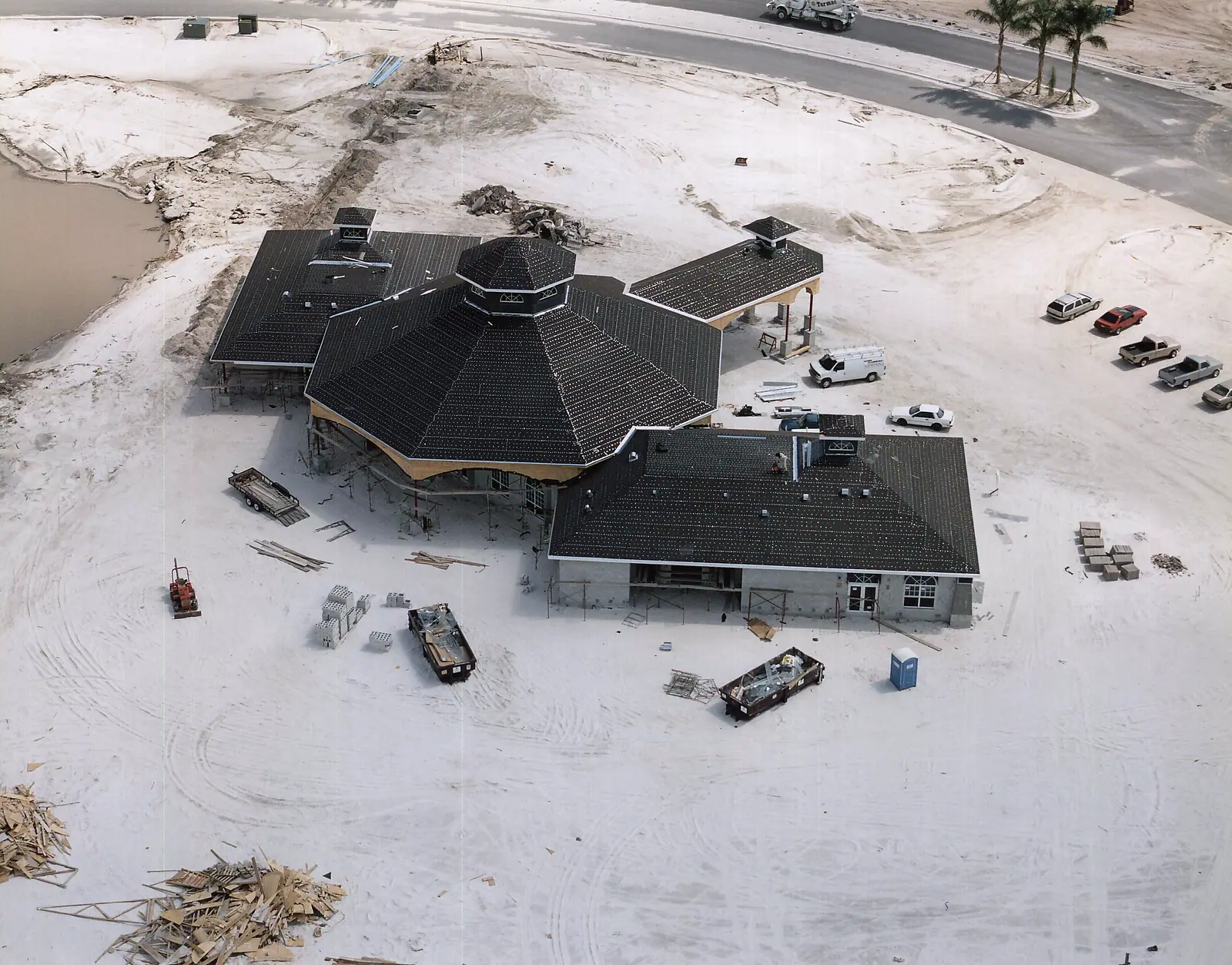 Aerial view of a clubhouse under construction with an octagonal roof and dry-in underlayment